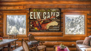 Wood elk sign hung up in log cabin as wall art decor from oldwoodsigns.com